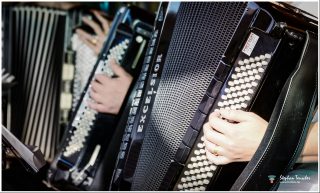 Dieses Foto ist als kostenloser Download (ohne Rand und Signatur) im Originalformat oder als Print zum Kauf/Mieten in meinem Shop auf <a href="https://butlaix.de/produkt/fotografie-akkordeon-accordion-no-2/" target="_blank" rel="noreferrer noopener" >BUTLAIX_media</a> verfügbar. Nahaufnahme von zwei Akkordeonspielern mit schwarzen Excelsior-Akkordeons. Hände bedienen die weißen Knöpfe und Tasten; sichtbar sind die charakteristischen Balgfalten und Metallgitter der Instrumente.