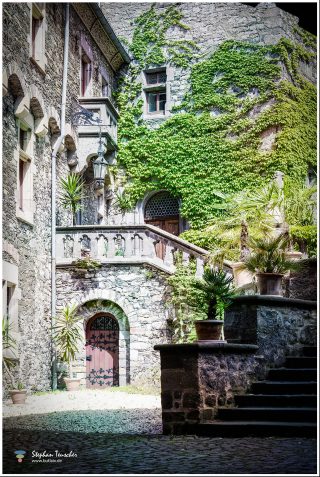 Dieses Foto ist als kostenloser Download (ohne Rand und Signatur) im Originalformat oder als Print zum Kauf/Mieten in meinem Shop auf <a href="https://butlaix.de/produkt/fotografie-schloss-braunfels-no-9/" target="_blank" rel="noreferrer noopener" >BUTLAIX_media</a> verfügbar. Schlosshof mit efeubewachsener Natursteinmauer, schmiedeeiserner Rundbogentür, gotischer Außentreppe, historischer Laterne und mediterranen Kübelpflanzen auf Kopfsteinpflaster.