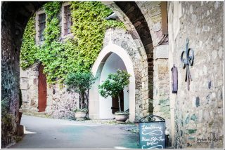 Dieses Foto ist als kostenloser Download (ohne Rand und Signatur) im Originalformat oder als Print zum Kauf/Mieten in meinem Shop auf <a href="https://butlaix.de/produkt/fotografie-schloss-braunfels-no-14/" target="_blank" rel="noreferrer noopener" >BUTLAIX_media</a> verfügbar. Schlosshof mit romanischem Torbogen, efeuberankte Natursteinmauer, gotischer Spitzbogeneingang mit zwei Kugelbaum-Kübeln. Kreidetafel: „Schlossführung – Kasse, Café & Shop geöffnet."