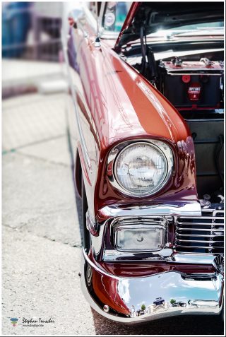 Dieses Foto ist als kostenloser Download (ohne Rand und Signatur) im Originalformat oder als Print zum Kauf/Mieten in meinem Shop auf <a href="https://butlaix.de/produkt/fotografie-oldtimer-no-7/" target="_blank" rel="noreferrer noopener" >BUTLAIX_media</a> verfügbar. Vorderansicht eines roten Oldtimers mit geöffneter Motorhaube, glänzender Chromstoßstange, rundem Scheinwerfer und Optima-Batterie sichtbar im Motorraum, aufgenommen bei einem Autotreffen.