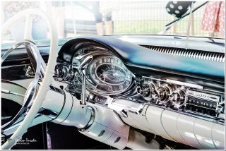 Dieses Foto ist als kostenloser Download (ohne Rand und Signatur) im Originalformat oder als Print zum Kauf/Mieten in meinem Shop auf <a href="https://butlaix.de/produkt/foto-oldtimer-no-13-als-poster-leinwand-bild-im-rahmen/" target="_blank" rel="noreferrer noopener" >BUTLAIX_media</a> verfügbar. Armaturenbrett eines klassischen amerikanischen Autos aus den 1950er Jahren mit verchromtem Lenkrad, rundem Tachometer, Radioknöpfen und schwarzen Plüschwürfeln am Rückspiegel.